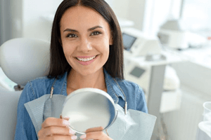 happy dental patient holding hand mirror
