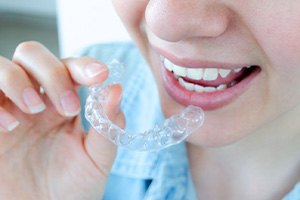 Woman holding Invisalign aligner close to her mouth