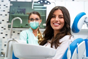 Smiling patient with dental team member in background