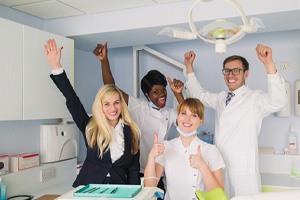 Happy dental team posing in treatment room