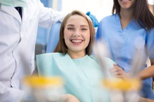 Happy dental patient with dental team members in background