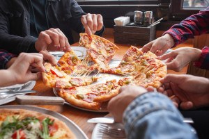 Friends reaching for slices of pizza