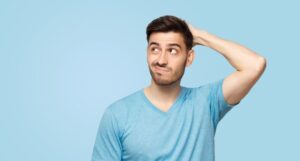 Confused man in blue t-shirt scratching his head