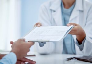 Doctor handing clipboard to patient